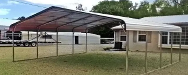 Farm-style steel carport with a rounded roof next to a house