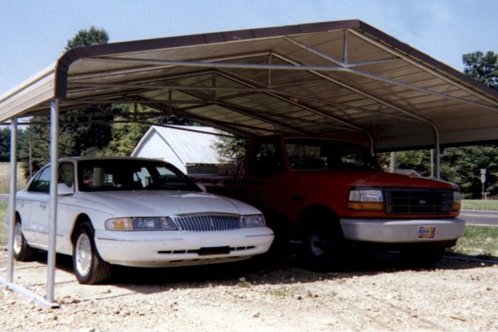 Wide steel carport covering a car and a pickup truck